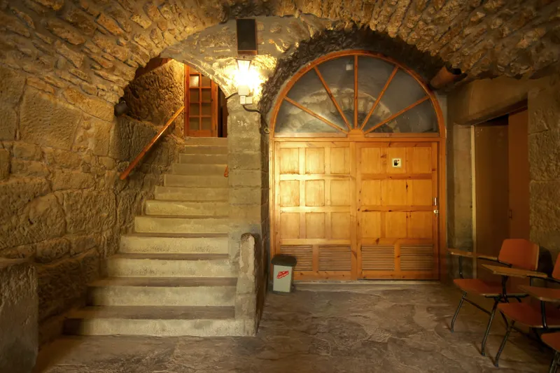 Entrada de la masia amb volta de pedra, escala i porta de fusta
