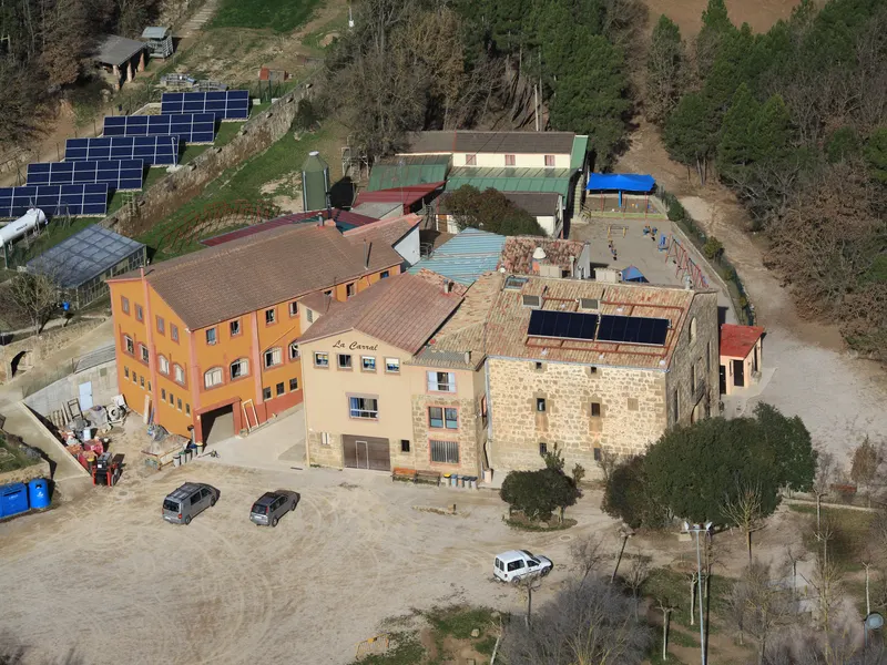 Els edificis de La Carral vistos des de dalt, amb la masia de pedra i les plaques solars